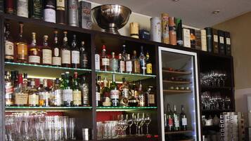 Un bar con estantes llenos de botellas de licor y vasos.