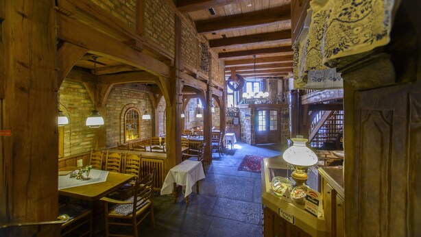 A rustic interior with wooden beams, stone walls, and a long dining area with tables and chairs. - Baumhove Hotel Restaurant Am Markt (Werne)