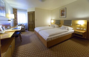 A hotel room with a double bed, a desk with a chair, a lamp, and a window with curtains. - Baumhove Hotel Restaurant Am Markt (Werne)