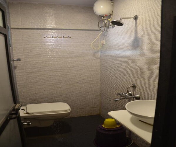 Un baño pequeño y funcional con inodoro, lavamanos y ducha.