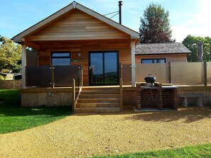 A wooden cabin with a covered porch, a grill, and a nameplate reading "Bluebell".