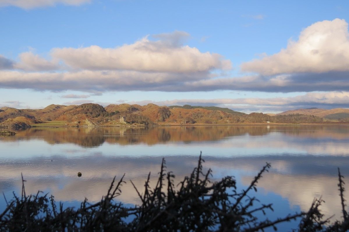 A calm lake with mountains in the background and a clear sky.