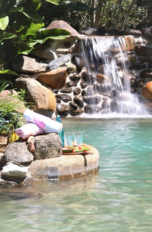 A waterfall cascading over rocks into a clear pool, surrounded by lush greenery. - Malanda Lodge (Malanda)