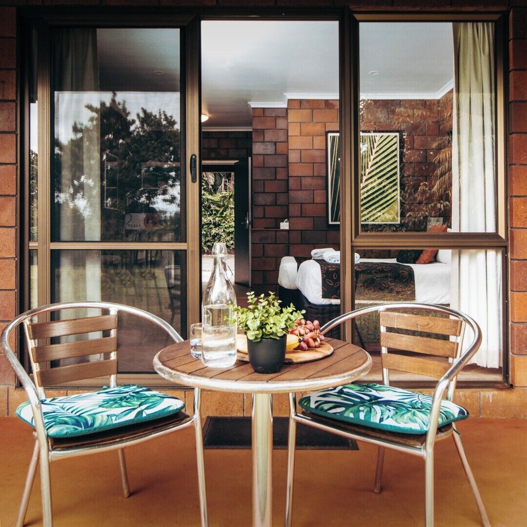 Ein Balkon mit zwei Stühlen, einem Tisch und einer Wasserflasche.