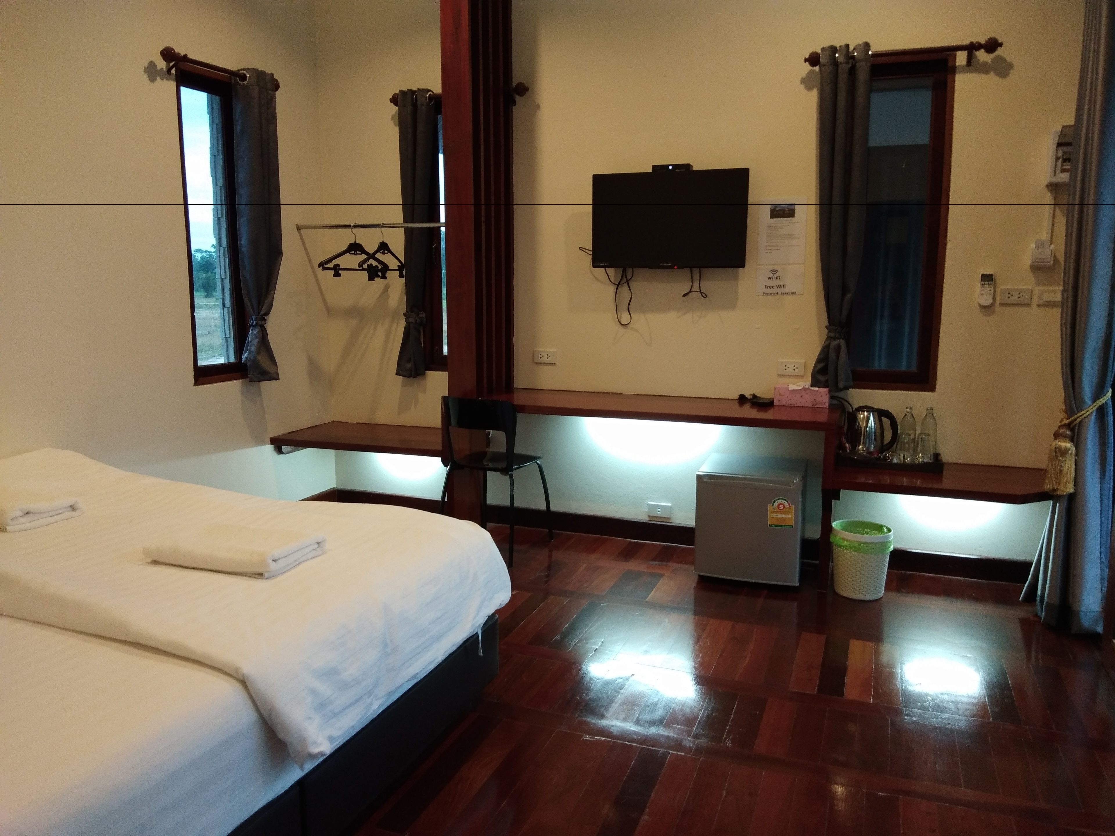 A hotel room with a bed, a desk, a television, and a small refrigerator.