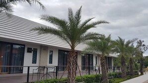 A modern building with a white exterior and large windows. There are palm trees and outdoor seating areas. - Ingaun Resort (Lao Khwan)