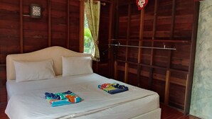 A wooden room with a bed, a window with a curtain, and a wall-mounted air conditioner. - Ingaun Resort (Lao Khwan)