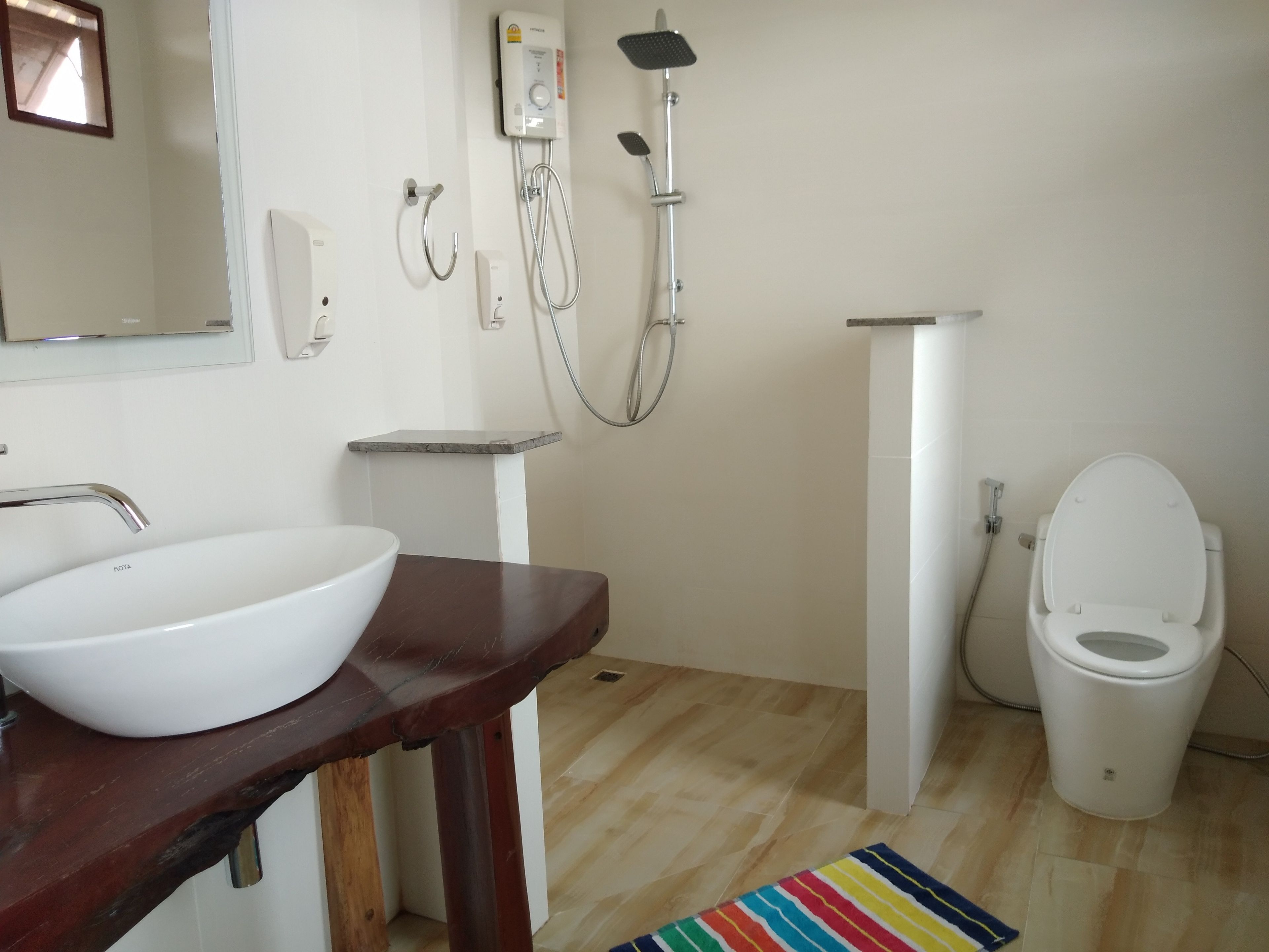 A bathroom with a white sink, a wooden vanity, a shower, and a toilet.