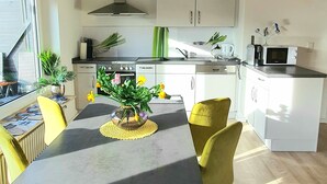 Uma cozinha moderna com vigas de madeira, armários brancos e uma área de jantar com mesa e cadeiras.