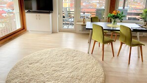 A modern living room with a dining area, large windows, and a flat-screen TV. - Sanosueno 1 - Traumhafter Bergblick (Sonthofen)