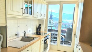 A kitchen with white cabinets, a wooden countertop, and a view through the glass door. - Sanosueno 2 - Toller Bergblick (Sonthofen)