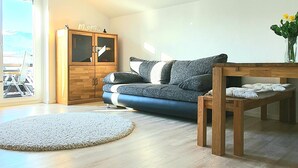 A modern living room with a sofa, wooden cabinet, and a round rug. - Sanosueno 2 - Toller Bergblick (Sonthofen)