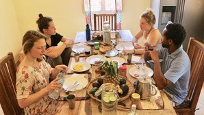 Eine Gruppe von Menschen genießt eine Mahlzeit an einem Holztisch mit verschiedenen Speisen, Getränken und Beilagen.
