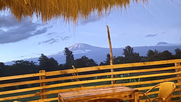 Eine Holzdielen-Terrasse mit Tisch und Stühlen mit Blick auf einen Berg.