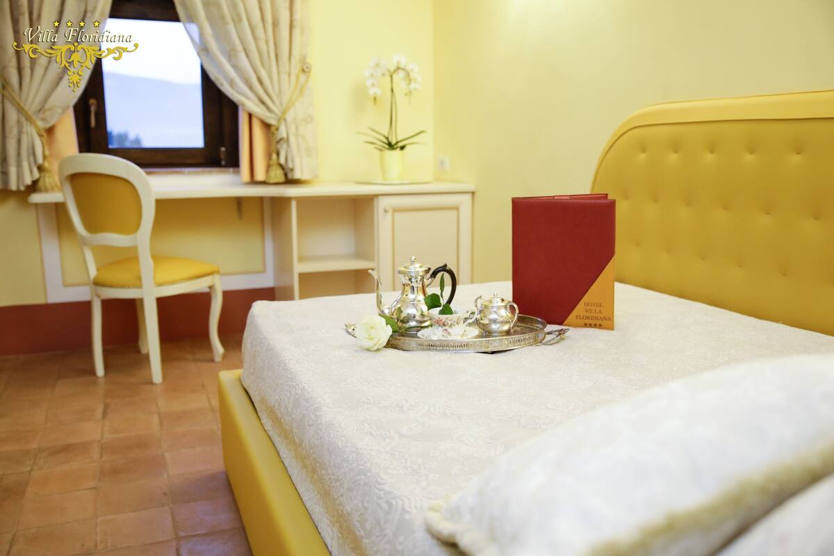 A hotel room with a bed, a desk, a chair, and a window with curtains.