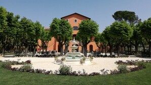 A courtyard with a fountain, outdoor seating, and a building with arched windows. - Villa Floridiana (Anagni)