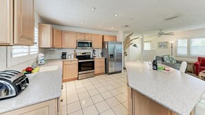 A modern kitchen with wooden cabinets, stainless steel appliances, and a granite countertop. - Dreamscape: North End Pool Home, 2 Blocks to Beach by Anna Maria Life Vacation Rentals (Anna Maria)