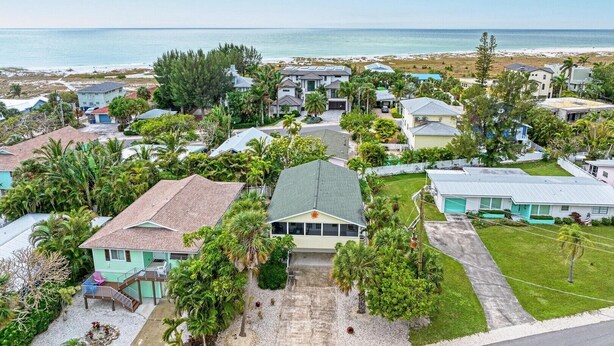 A coastal residential area with houses, some with visible driveways and front yards, and a beach in the background. - Dreamscape: North End Pool Home, 2 Blocks to Beach by Anna Maria Life Vacation Rentals (Anna Maria)