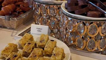A buffet with various desserts including cakes, pastries, and a plate of what appears to be a type of fudge.