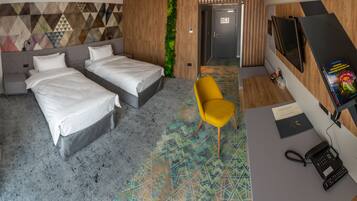 A hotel room with two beds, a desk with a phone, a TV, and a colorful carpet.
