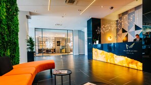 A modern hotel reception area with a reception desk, seating area, and a visible restaurant in the background. - Mandachi Hotel & SPA (Suceava)