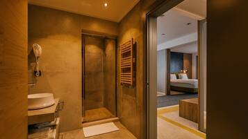 A modern bathroom with a glass shower, a sink, and a towel rack.