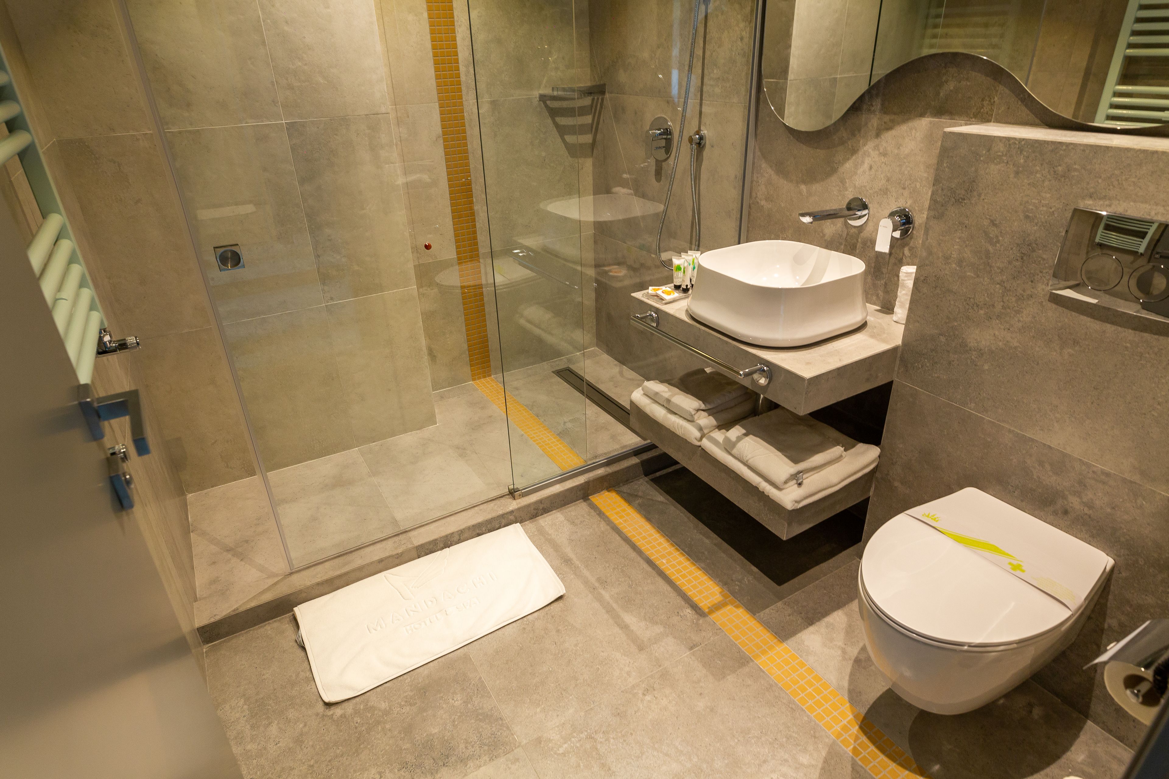 A modern bathroom with a glass shower enclosure, a white sink, and a toilet.