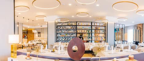 A modern hotel lobby with a wine cellar, round ceiling lights, and a central decorative piece.