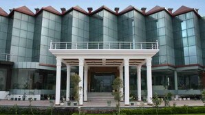A modern building with a glass facade and a central entrance with a covered porch. - Hotel Padmini Palace (Rishikesh)