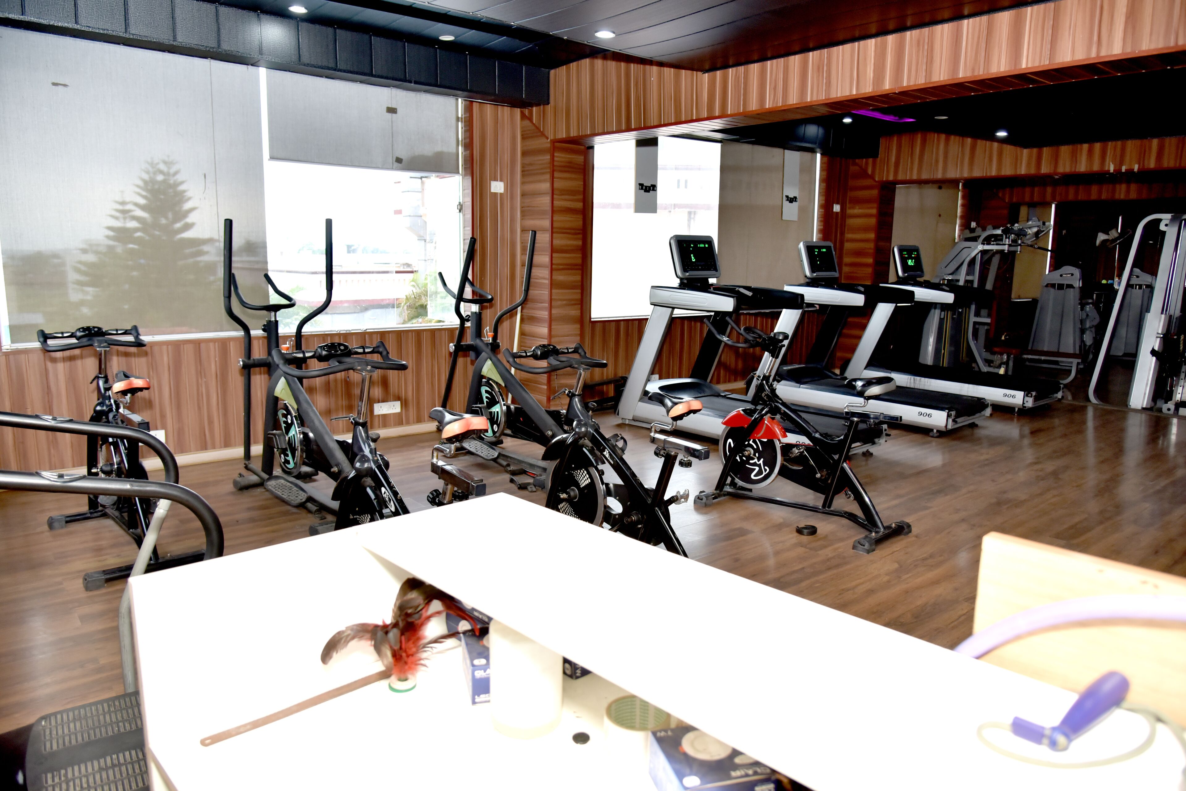 Un gimnasio con diversos equipos de ejercicio, incluyendo cintas de correr y bicicletas estáticas, y un amplio ventanal que ofrece vistas al exterior.