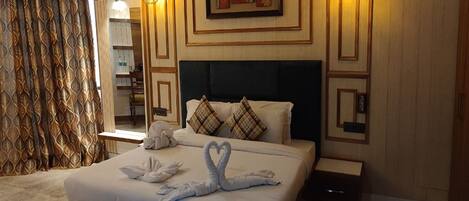 A hotel room with a bed, a nightstand, a lamp, and a wall with a decorative panel.