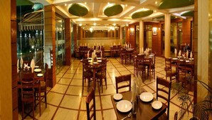 Un restaurante amplio con varias mesas y sillas, suelo de baldosas y un diseño moderno en el techo con detalles verdes.