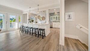 A spacious kitchen with a central island, bar stools, and a view to the outside.
