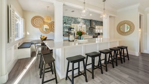 A modern kitchen with a central island, bar stools, and pendant lighting.