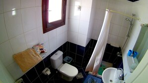 Et lille badeværelse med toilet, håndvask og bruser.