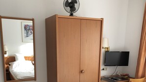 A hotel room with a bed, a wooden wardrobe, a desk with a computer, a chair, a desk lamp, and a wall-mounted TV. - Hotel-Restaurant Reher Hof (Hagen)