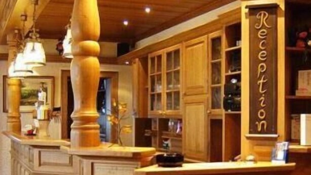 A reception area with wooden cabinetry, a reception desk, and a sign that reads "Reception". - Hotel-Restaurant Reher Hof (Hagen)