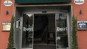 A hotel entrance with a sign reading "Hotel Restaurant Reher Hof" and a coat of arms. There are two potted plants at the entrance. - Hotel-Restaurant Reher Hof (Hagen)