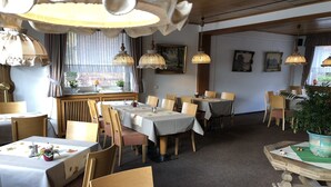 A restaurant interior with multiple tables and chairs, hanging lamps, and framed artwork on the walls. - Hotel-Restaurant Reher Hof (Hagen)