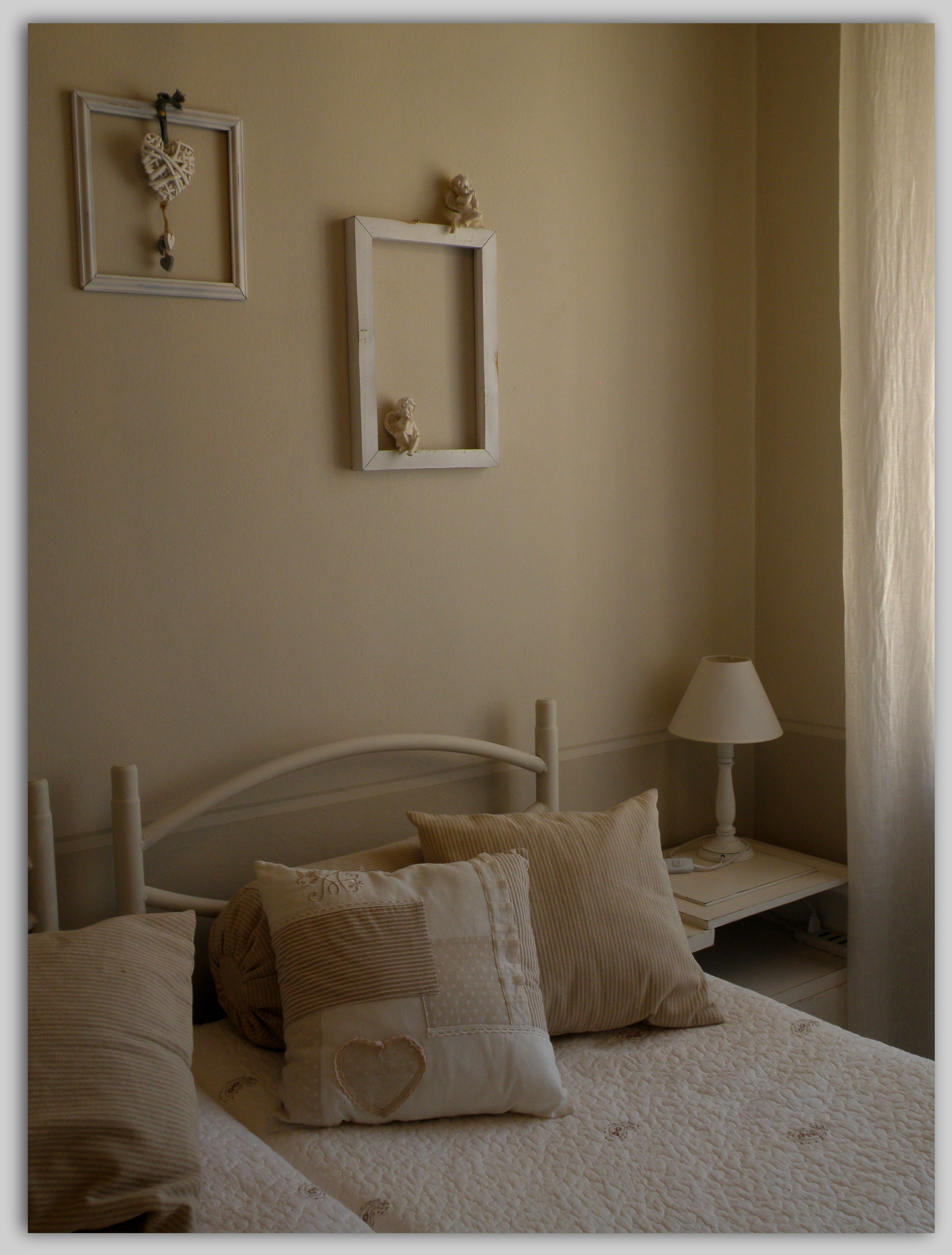 A bedroom with two beds, a bedside table with a lamp, and decorative items on the wall.