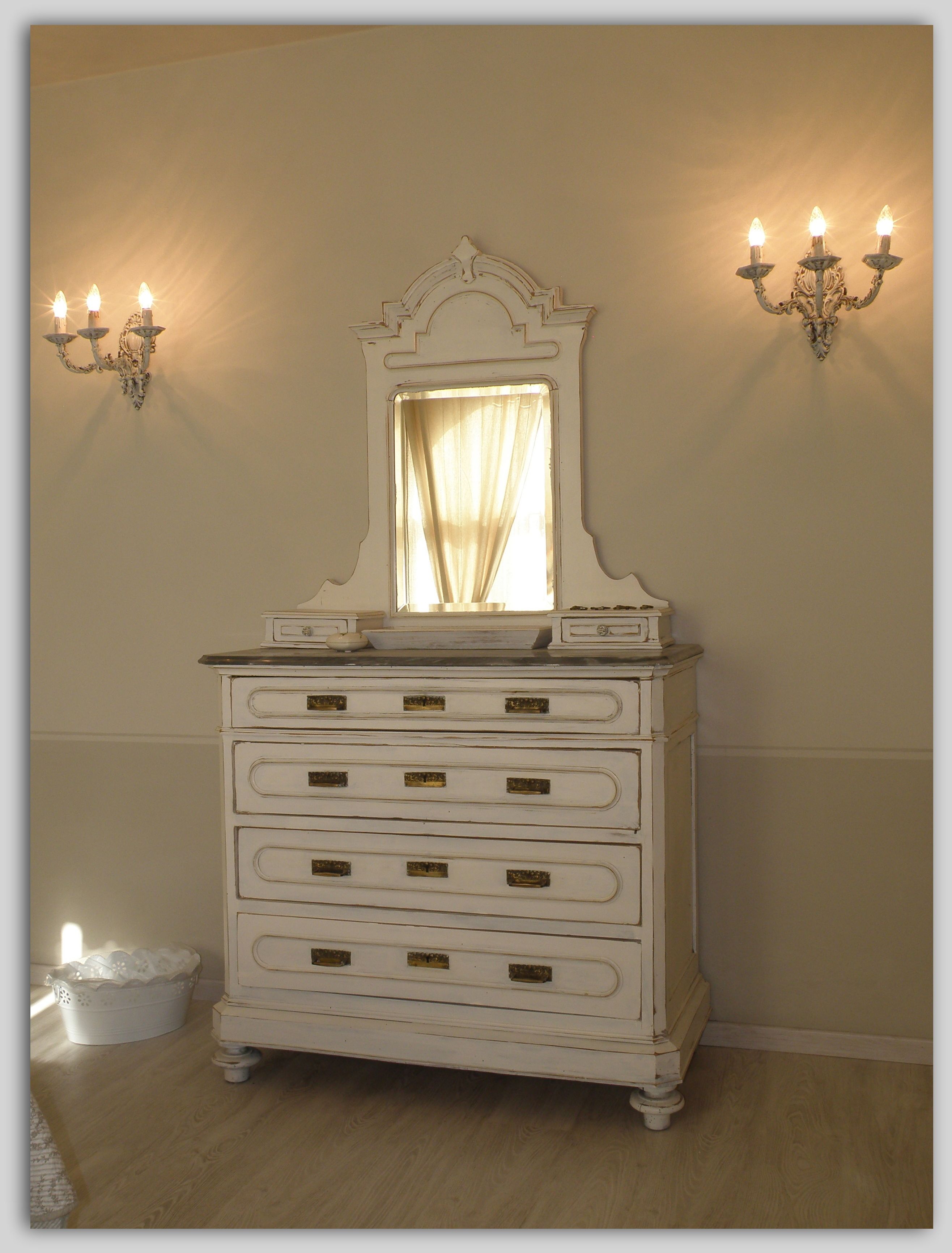 Een witte dressoir met spiegel en drie wandlampen.