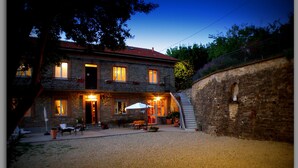 A stone building with a red-tiled roof, a balcony, and a staircase leading to an upper floor. - Cascina Luvot (Melazzo)