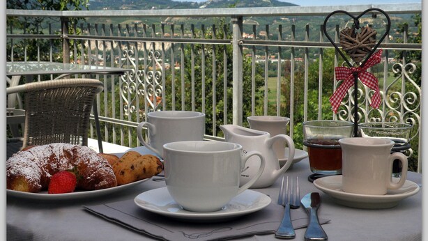 A table set with pastries, cups, and a teapot on a balcony with a scenic view. - Cascina Luvot (Melazzo)