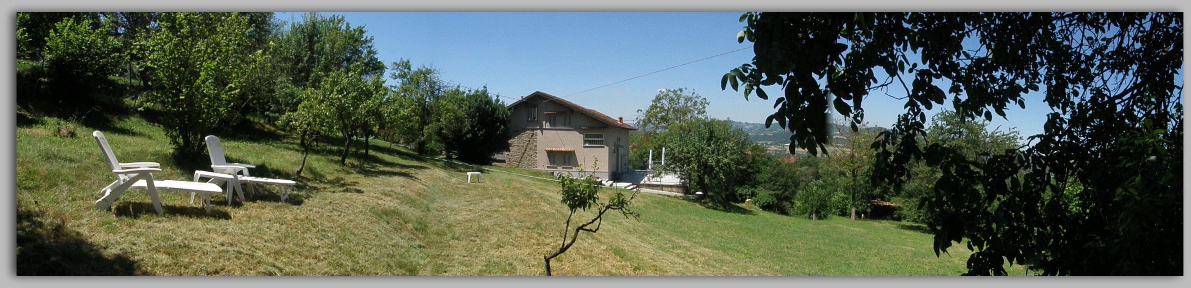Uma casa com fachada de pedra, rodeada por uma área gramada com árvores.