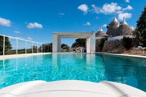 A swimming pool with a stone structure and a white archway.
