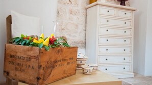 Ein Holzkoffer mit Blumen, eine weiße Kommode mit Schubladen und Keramiktassen auf einem Tisch.