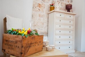Een houten kist met bloemen, een witte dressoir met lades, en keramische bekers op een tafel.