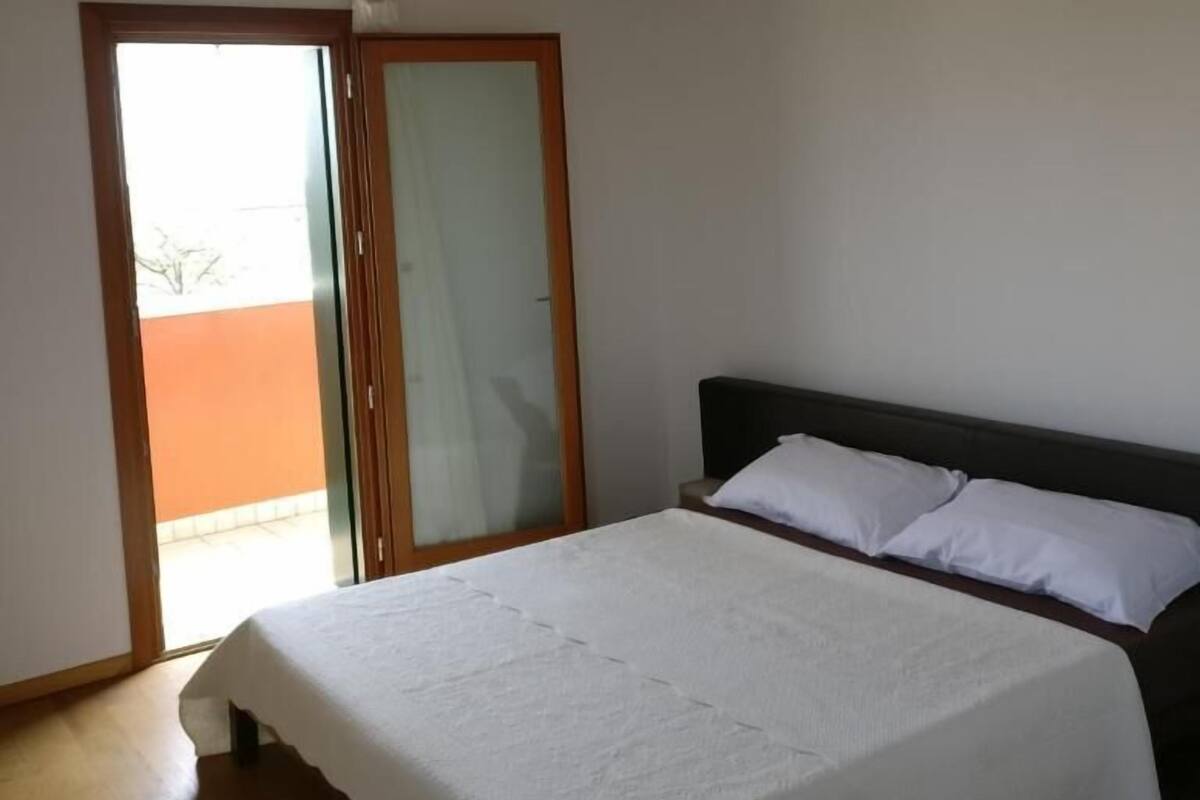 Un dormitorio con cama, techo de madera, puerta corredera de vidrio y vista al exterior.