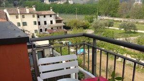 A balcony with a red checkered table set for two, overlooking a scenic landscape with buildings and trees. - Oleaclub Locazione Turistica (Maser)