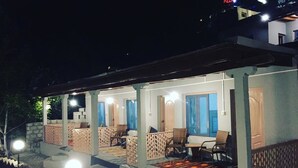 A covered outdoor seating area with tables and chairs, a stone wall, and a sign indicating a pizza place. - Baltit Heritage Inn (Karimabad)